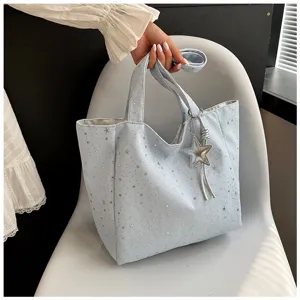 Detail shot of light blue large capacity tote bag featuring silver star print and charm