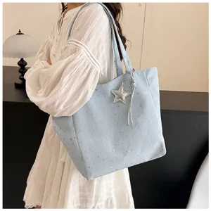 Light blue large tote bag with star patterns and charm detail shown on a shoulder.