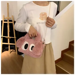 Detalle del bolso de peluche rosa con ojos grandes y correa de cadena dorada