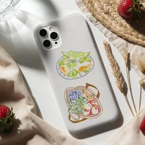 Dettaglio di adesivi trasparenti con frutta disegnati a mano applicati su una cover per telefono