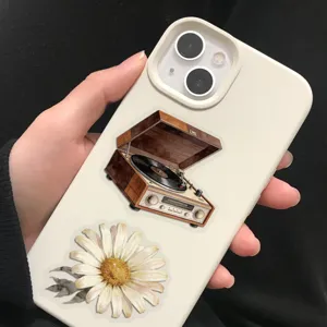 Close-up of vintage record player and daisy stickers applied on a white smartphone case