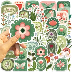 Gros plan d'autocollants floraux de forêt vintage tenus à la main pour projets de décoration DIY