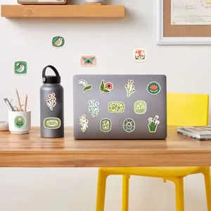 Détail de stickers floraux vintage appliqués sur un ordinateur portable et une gourde sur un bureau
