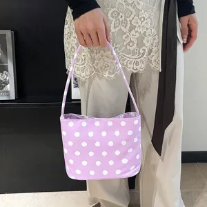 Detailopname van een lavendelkleurige schoudertas met stippen en een zomerse outfit