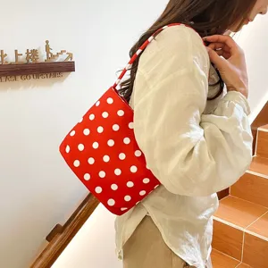 Gedetailleerd vooraanzicht van een vrouw met een rood-witte stippen schoudertas op trap