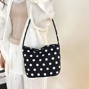 Elegante zwart-witte schoudertas met stippen gedragen door model in witte kleding