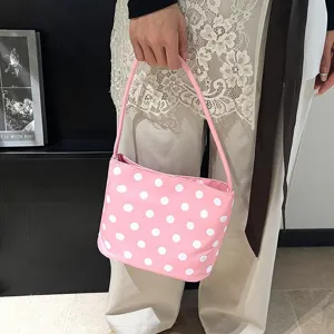 Detail van een stijlvolle roze handtas met stippen vastgehouden door een model in outfit