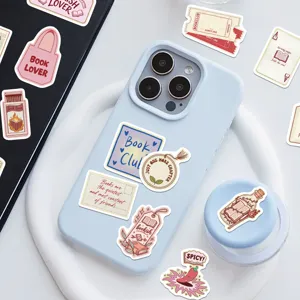 Aesthetic bookish stickers decorating a light blue phone case and white desk surface