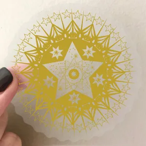 Close-up detail of a gold foil PET sticker featuring a complex star and moon mandala design