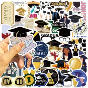 Dettaglio dell'adesivo di laurea tenuto in mano con tocco sui libri per la festa del 2026