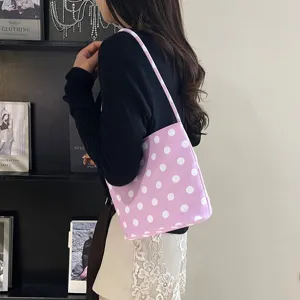 Detail van een roze onderarmtas met polkadots gedragen door een model voor deze mode