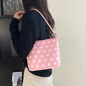 Zijaanzicht van model met een stijlvolle roze schoudertas met stippen voor de zomer