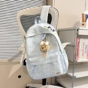 Gedetailleerd aanzicht van de lichtblauwe rugzak met een schattige pluche beer hanger.