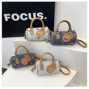 Detailed view of four mini denim Boston bags with cherry and bow embroidery patterns.