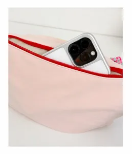 Detail showing the rear zipper pocket on a pink crossbody bag with a smartphone inside.