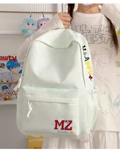 Détail d'un sac à dos d'écolier vert menthe avec broderie de lettres tenu par un modèle