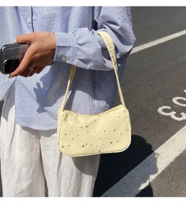 Primer plano de un elegante bolso de hombro crema con un delicado estampado de estrellas