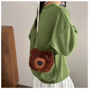 Detailed view of a cute brown plush bear crossbody bag on a green sweatshirt