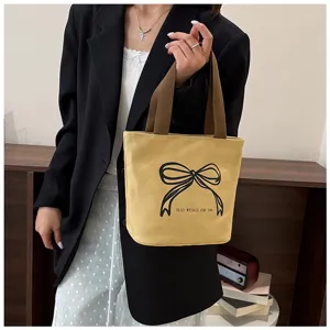 Modelo con bolso tote de lona beige con estampado de lazo negro en entorno real