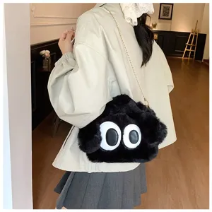 Detalle de un lindo bolso peludo negro con ojos grandes, bolso de hombro cruzado