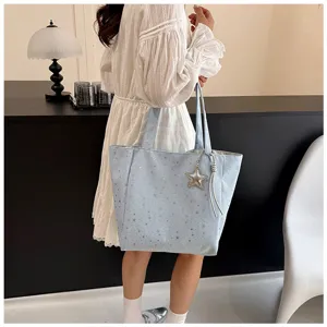Lifestyle view showing a light blue large capacity tote bag with silver star pattern and charm.