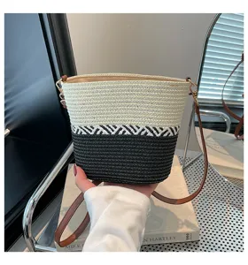 Vista detallada del bolso tipo cubo de paja tejida a mano con diseño color-block
