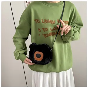Fluffy black plush bear crossbody shoulder bag worn by a model in a green sweatshirt