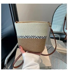 Detalle de un bolso cubo de paja tejido a mano con un elegante diseño de rayas.
