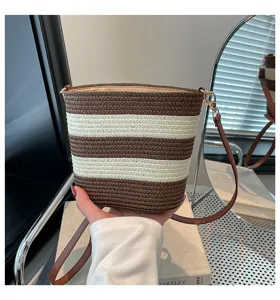 Vista de detalle de un bolso de paja trenzada a rayas con elegante correa de cuero.