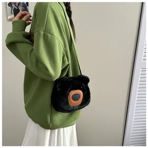 Close-up detail of cute black plush bear crossbody bag styled with a green sweatshirt.
