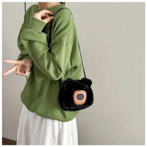 Detail of cute black plush bear crossbody bag styled with green sweatshirt and skirt