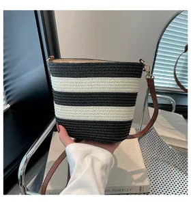 Detalle de un bolso tipo cubo de paja trenzada a rayas blancas y negras hecho a mano con asa
