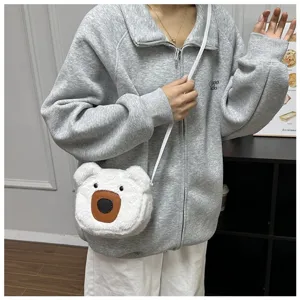 Close-up of cute white plush bear crossbody bag worn with a casual grey hoodie outfit