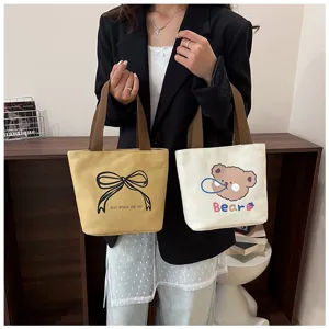 Detalle de bolsos tote de lona amarillo mostaza y blanco roto con bonitos diseños
