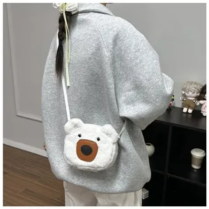 Close-up detail of a model carrying a cute white plush bear-shaped crossbody bag in a room