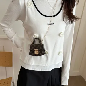 Detailed view of a mini brown monogram crossbody bag worn on a white floral top