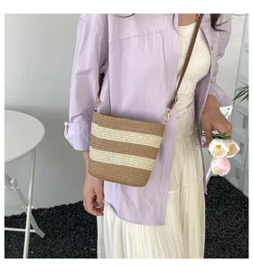 Detalle de bolso saco de paja a rayas con camisa morada para un estilo muy playero.