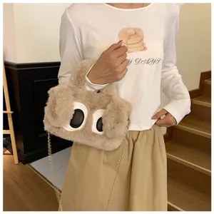 Vista detallada de un bolso de peluche caqui con ojos grandes y correa de cadena