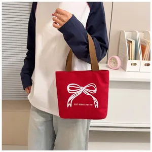 Primer plano de un bolso tote de lona roja con un lazo blanco y detalles de texto