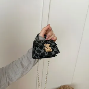 Close-up of mini crossbody bag showing M-pattern leather and gold lock hardware