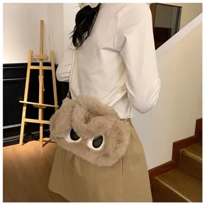 Vista detallada de un bolso de hombro de felpa con ojos grandes llevado por una modelo