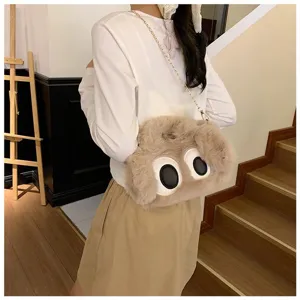 Detalle de un bolso bandolera de peluche con ojos grandes, llevado por una modelo.