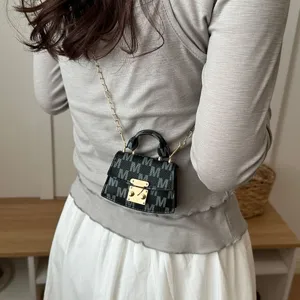 Close-up of a luxury mini accessory bag with M pattern and golden chain strap