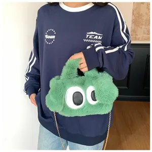 Primer plano de un bolso de peluche verde con ojos grandes llevado por una modelo.