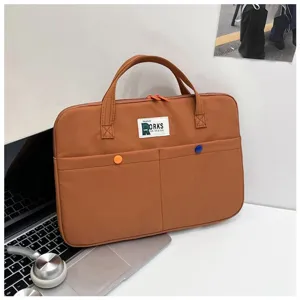 Détail d'une mallette d'ordinateur portable marron avec deux poches et des fermetures orange.
