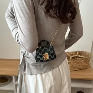 Detailed view of a micro crossbody bag with M-pattern and gold chain strap