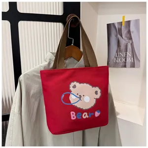 Bolso tote de lona roja con estampado de oso y asas de color marrón.