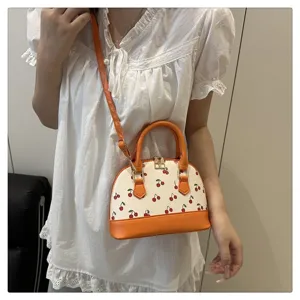 Nahaufnahme einer modischen orange-weißen Kirschprint-Muschelhandtasche an einem Model