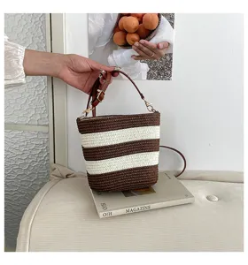 Vista manual de un bolso saco de paja tejida a rayas para las vacaciones de verano.