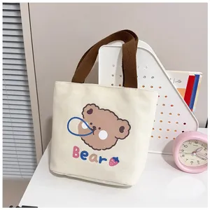 Vista detallada de un bolso de lona con oso lindo en un escritorio blanco moderno